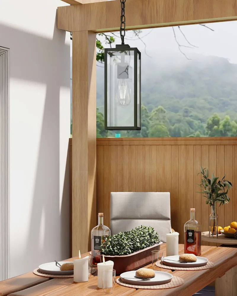 A black modern farmhouse outdoor hanging lantern from Dreamsidea suspended over a dining table on a serene, nature-view patio.